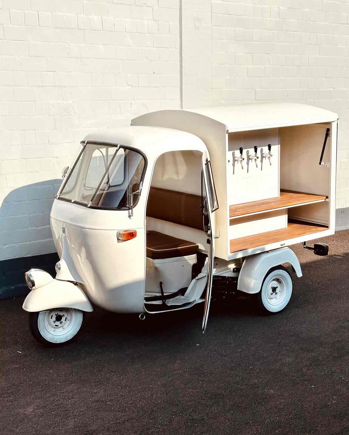 Mobile Cocktail Bar Typ System Gloria Ein kleiner Ape Piaggio in cremeweiß und Holzfarben mit integriertem Cocktails on Tap-System.